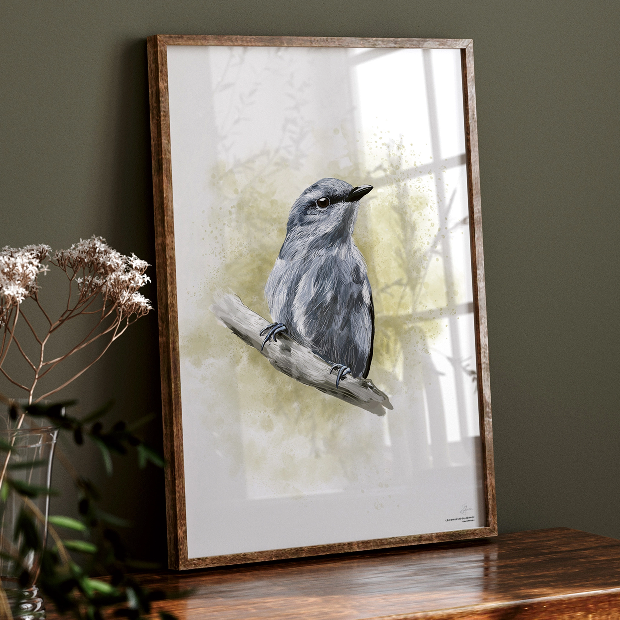 Image d'un portrait encadré d'un oiseau, posé sur un meuble ancien en bois, orné d'un bouquet de fleurs. Les bordures du cadre sont en bois foncé. À l'intérieur du cadre se trouve une illustration colorée d'un oiseau aux nuances bleu/violet, accroché à une branche. L'arrière-plan est un fond coloré vert pomme, façon tâches d'aquarelle.